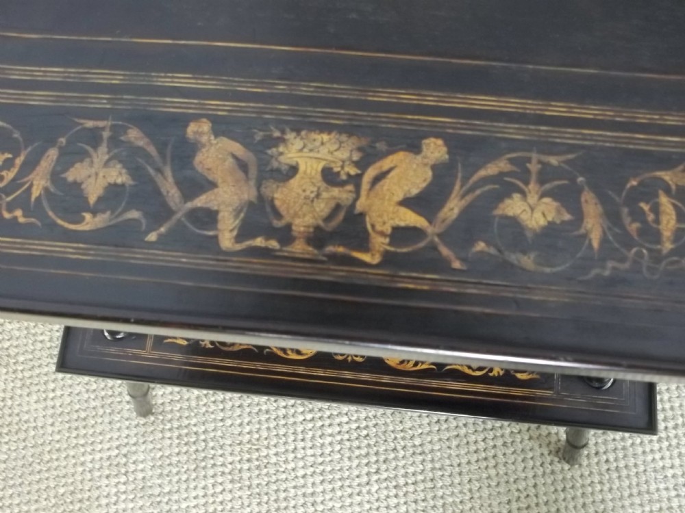 An ebonised two-tier side table displaying Sorrento marquetry inlay depicting a central chariot scene surrounded by decorative foliage and resting on turned legs. View V
