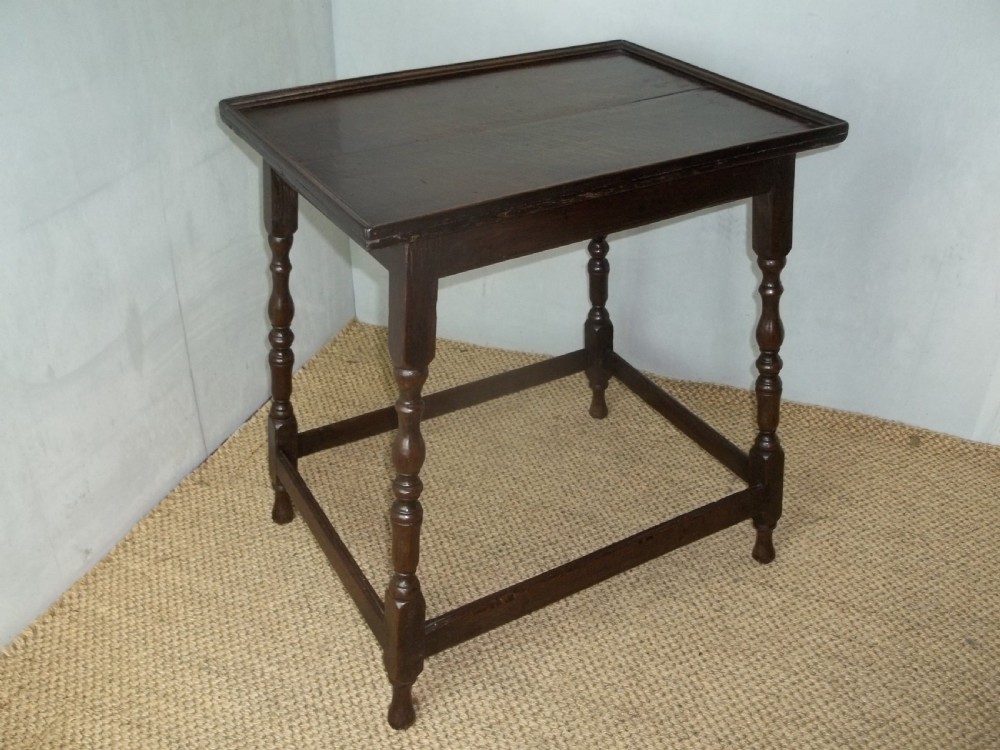 A dark brown oak side table featuring a tray top with a raised moulded rim, turned legs, and a low rectangular box stretcher base. View II