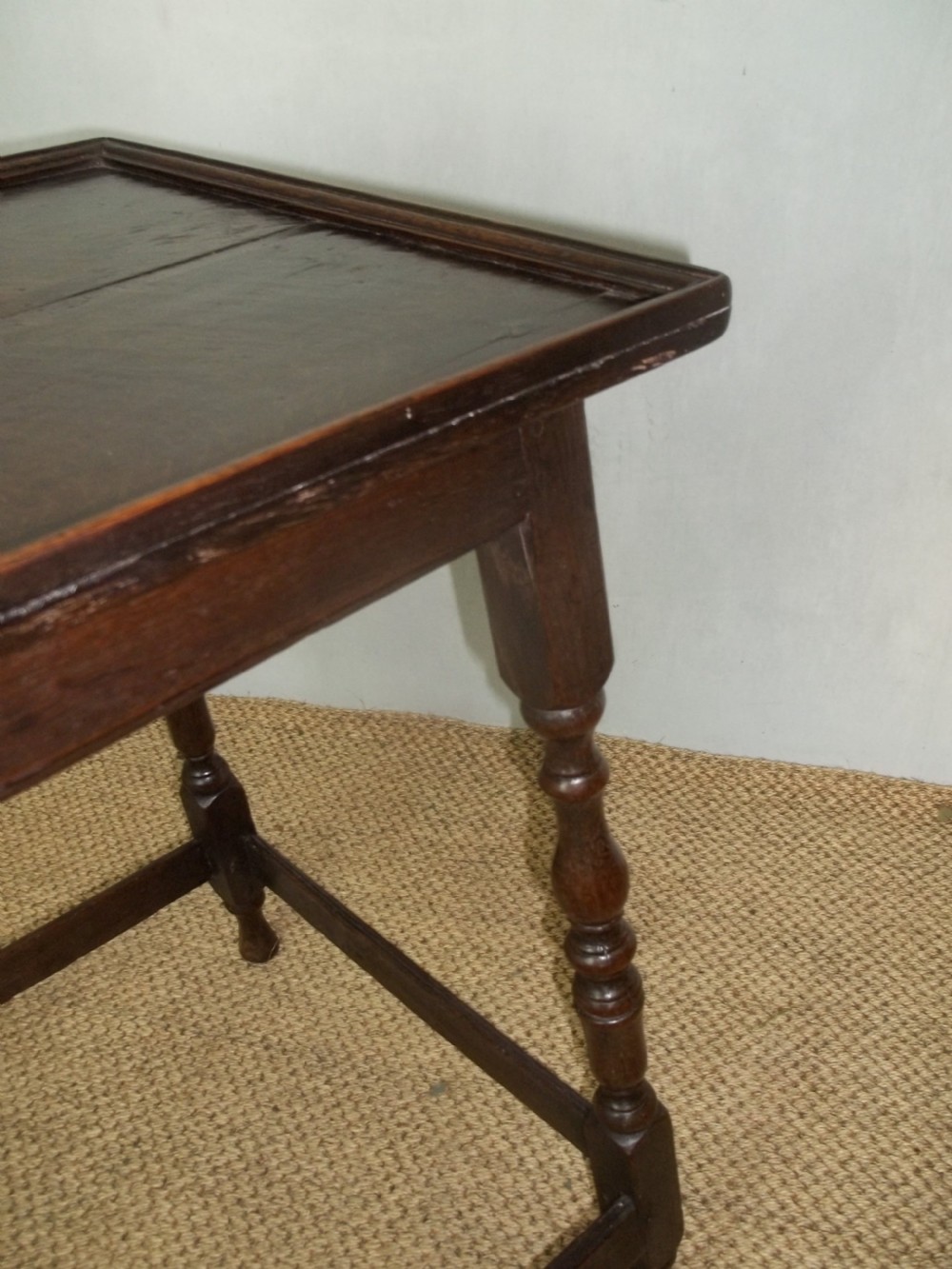 A dark brown oak side table featuring a tray top with a raised moulded rim, turned legs, and a low rectangular box stretcher base. View V