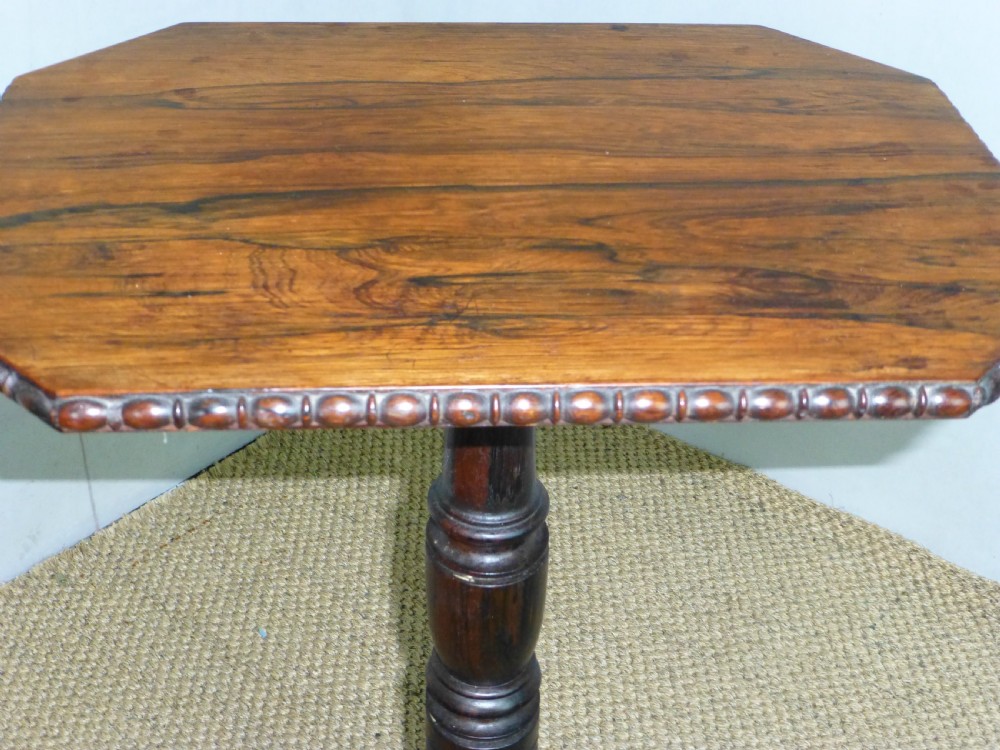 A Regency era rosewood occasional wine table featuring an octagonal top with beaded edging, a turned central pedestal, and three downswept tripod legs. View III