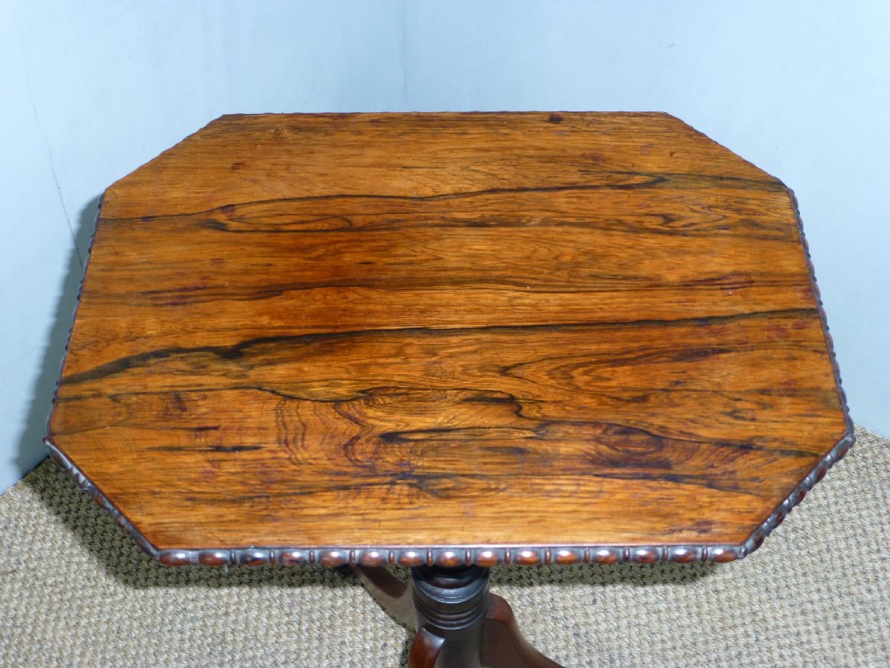 A Regency era rosewood occasional wine table featuring an octagonal top with beaded edging, a turned central pedestal, and three downswept tripod legs. View V