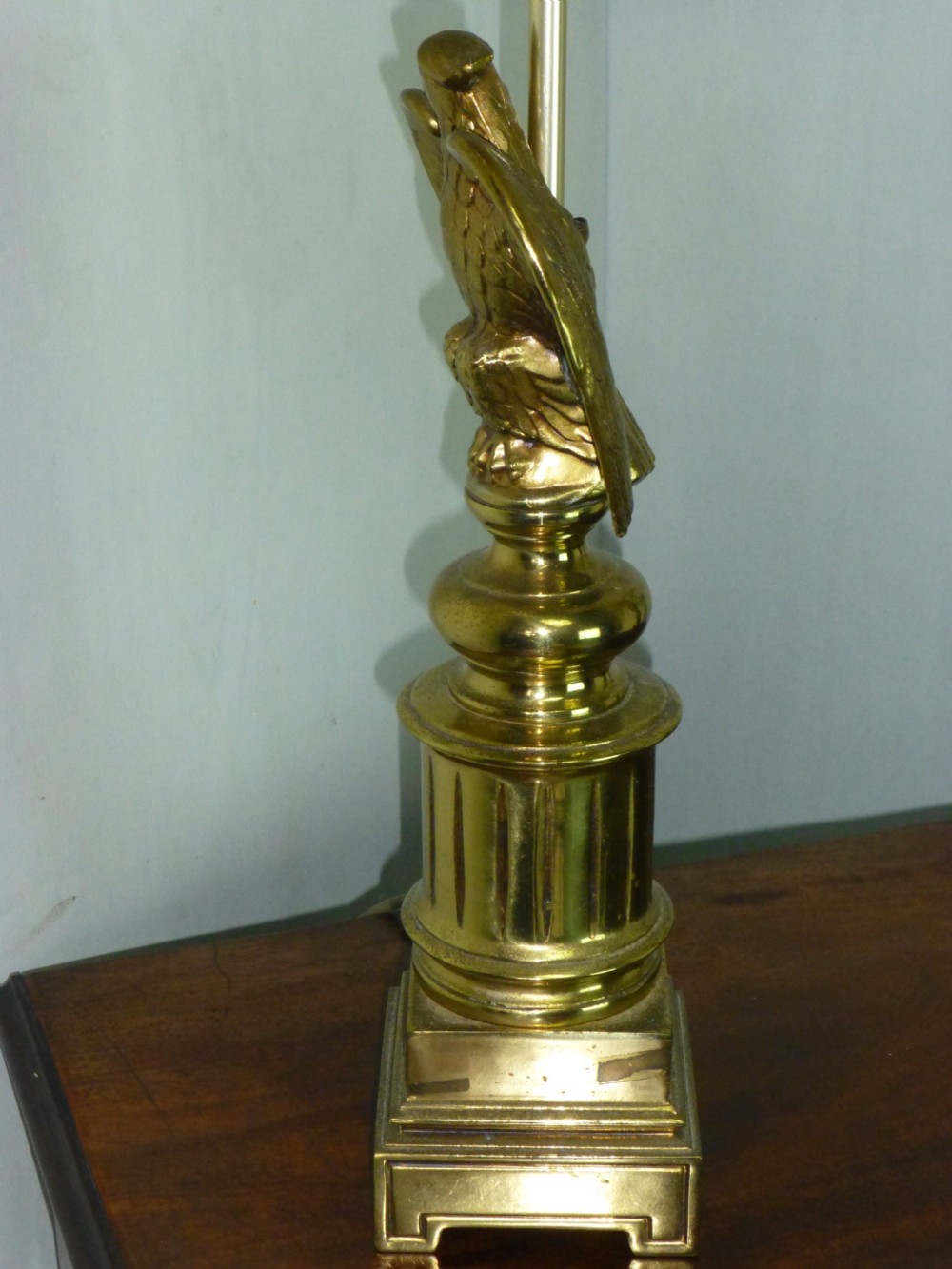 A pair of cast brass table lamps featuring eagle sculptures on stepped pedestal bases with cream pyramid shades. View IV