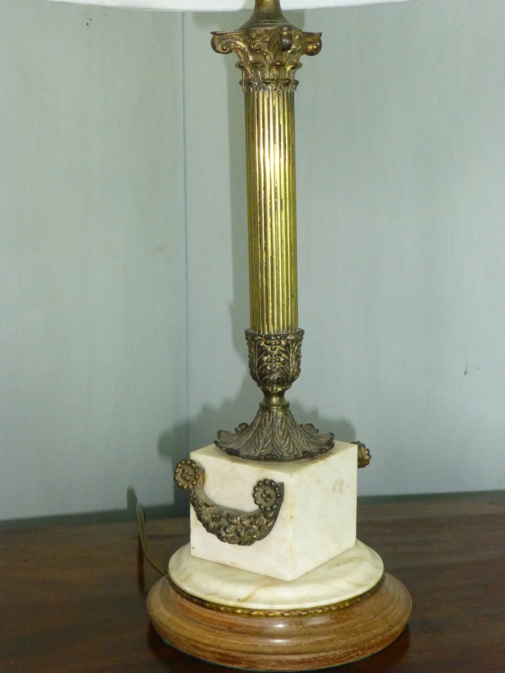 An antique Edwardian table lamp featuring a fluted brass column on a white marble plinth with a pleated cream shade. View II