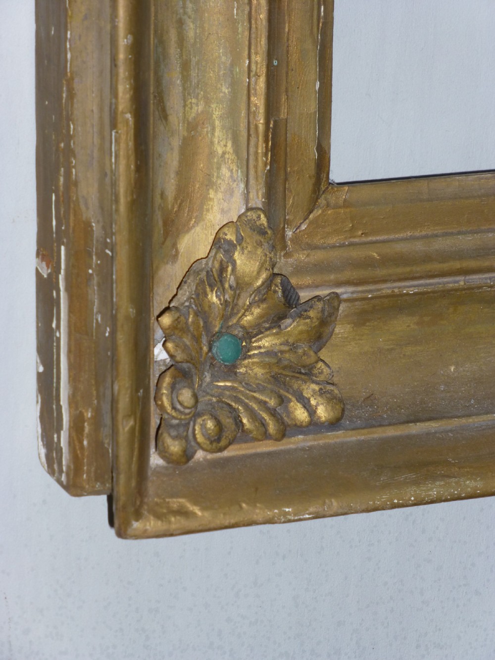 A square 19th-century giltwood frame featuring deep cove mouldings and carved acanthus leaf corner ornaments against a white wall. View III