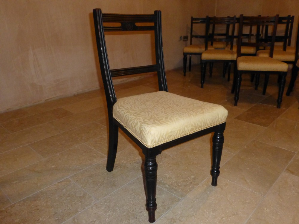 A set of ten 19th-century Victorian dark mahogany dining chairs featuring carved back rails, turned front legs, and yellow patterned fabric upholstered seats. View VII