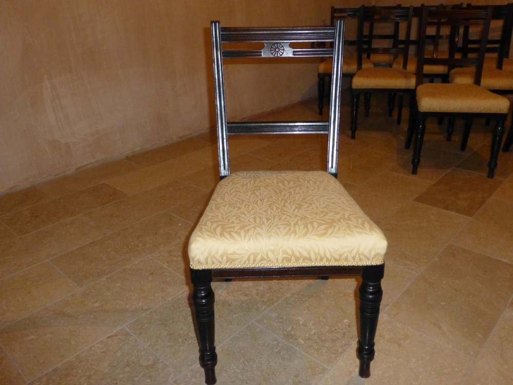 A set of ten 19th-century Victorian dark mahogany dining chairs featuring carved back rails, turned front legs, and yellow patterned fabric upholstered seats. View VIII