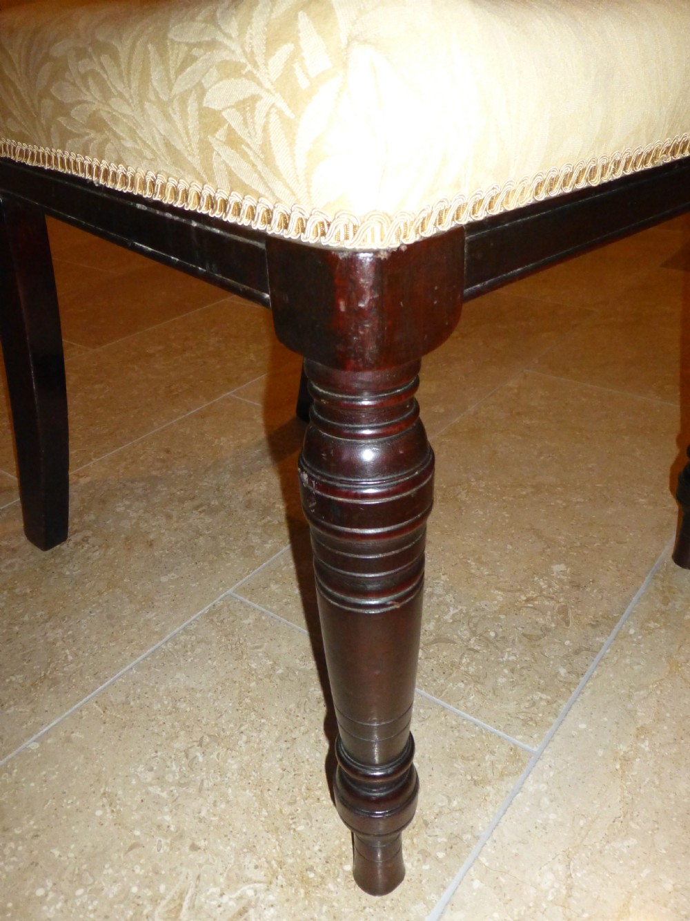 A set of ten 19th-century Victorian dark mahogany dining chairs featuring carved back rails, turned front legs, and yellow patterned fabric upholstered seats. View X