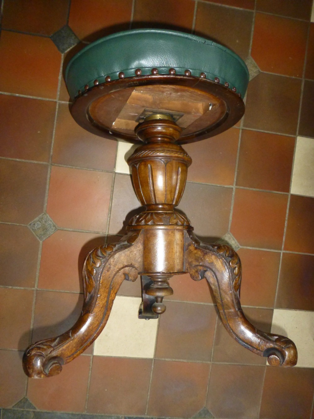 A 19th-century Victorian revolving piano stool featuring a deep green leather buttoned seat mounted on a carved walnut tripod base. View II