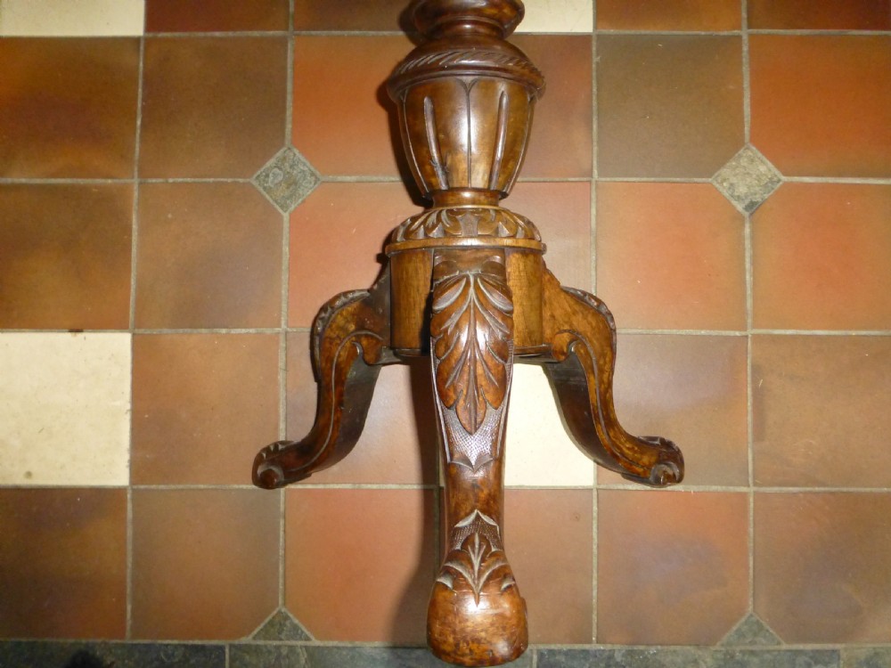 A 19th-century Victorian revolving piano stool featuring a deep green leather buttoned seat mounted on a carved walnut tripod base. View V