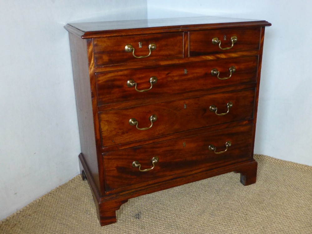 An 18th-century Georgian mahogany chest of drawers featuring two short over three long drawers with brass swan-neck handles and bracket feet.