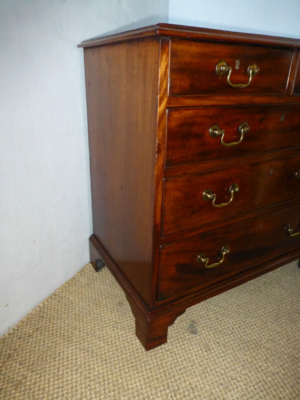 An 18th-century Georgian mahogany chest of drawers featuring two short over three long drawers with brass swan-neck handles and bracket feet. View V