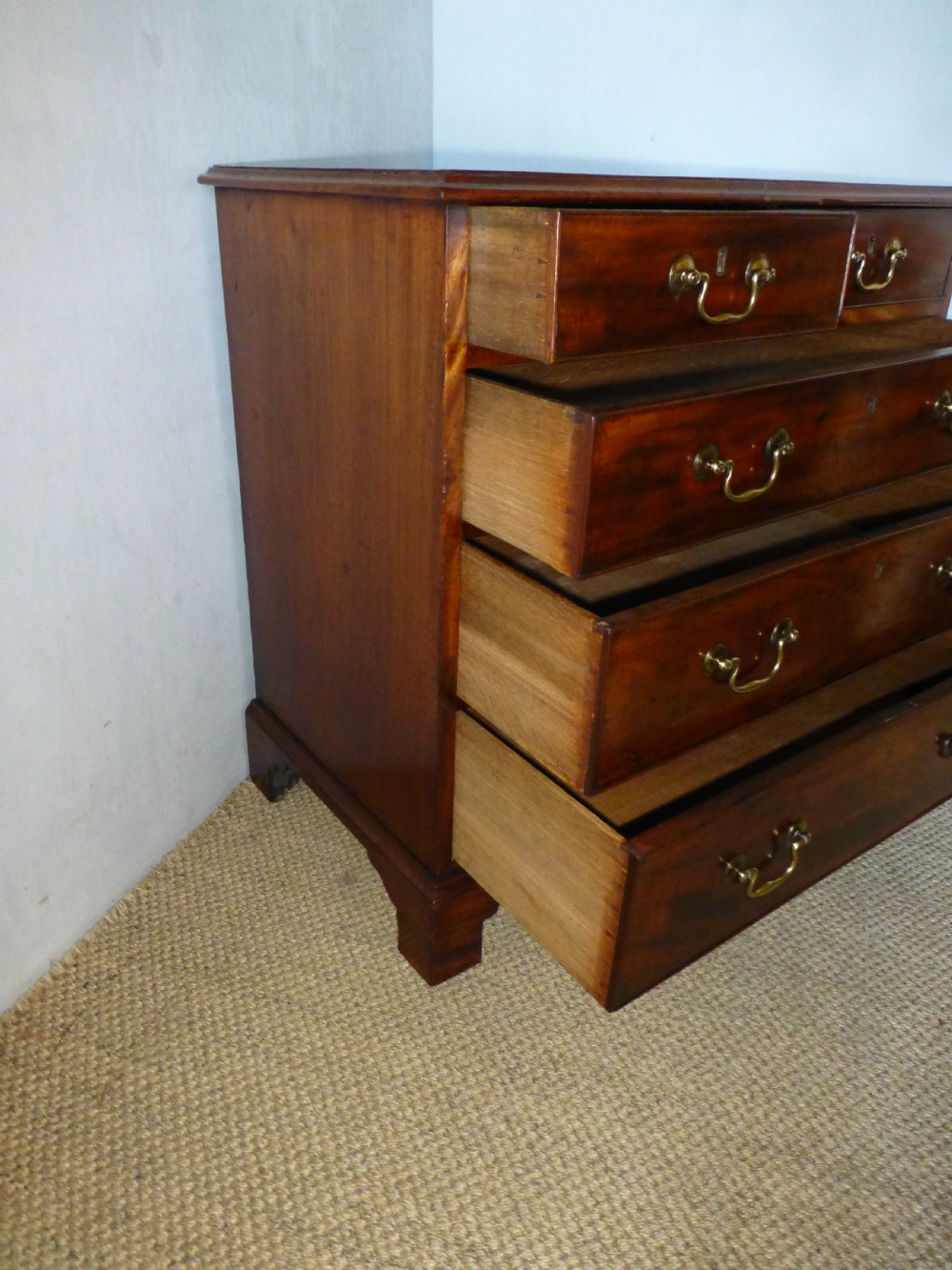 An 18th-century Georgian mahogany chest of drawers featuring two short over three long drawers with brass swan-neck handles and bracket feet. View VI