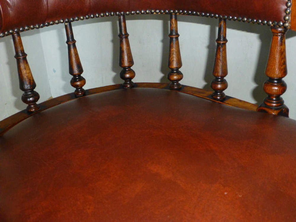 A Victorian oak captains desk chair with button-backed chestnut brown leather upholstery, turned spindles, and brass stud trim. View III