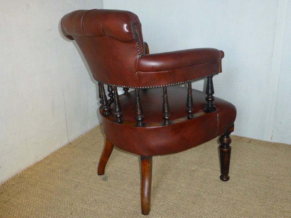 A Victorian oak captains desk chair with button-backed chestnut brown leather upholstery, turned spindles, and brass stud trim. View IV