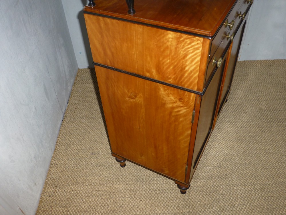A Regency satinwood chiffonnier desk featuring two tiered upper shelves with ebonised turned supports above drawers and a double cupboard door cabinet. View V