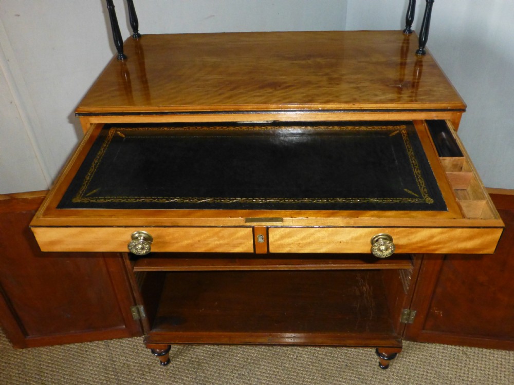 A Regency satinwood chiffonnier desk featuring two tiered upper shelves with ebonised turned supports above drawers and a double cupboard door cabinet. View X