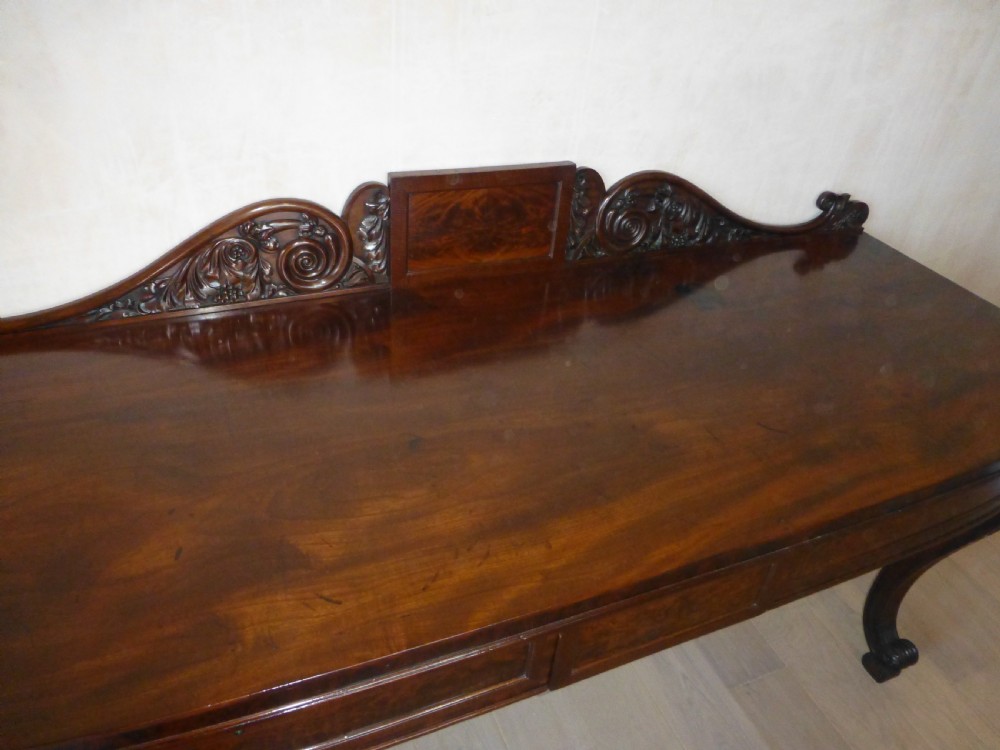 A dark mahogany Regency serving table featuring a scroll-carved backboard, a smooth top surface, and carved scroll front legs. View IX