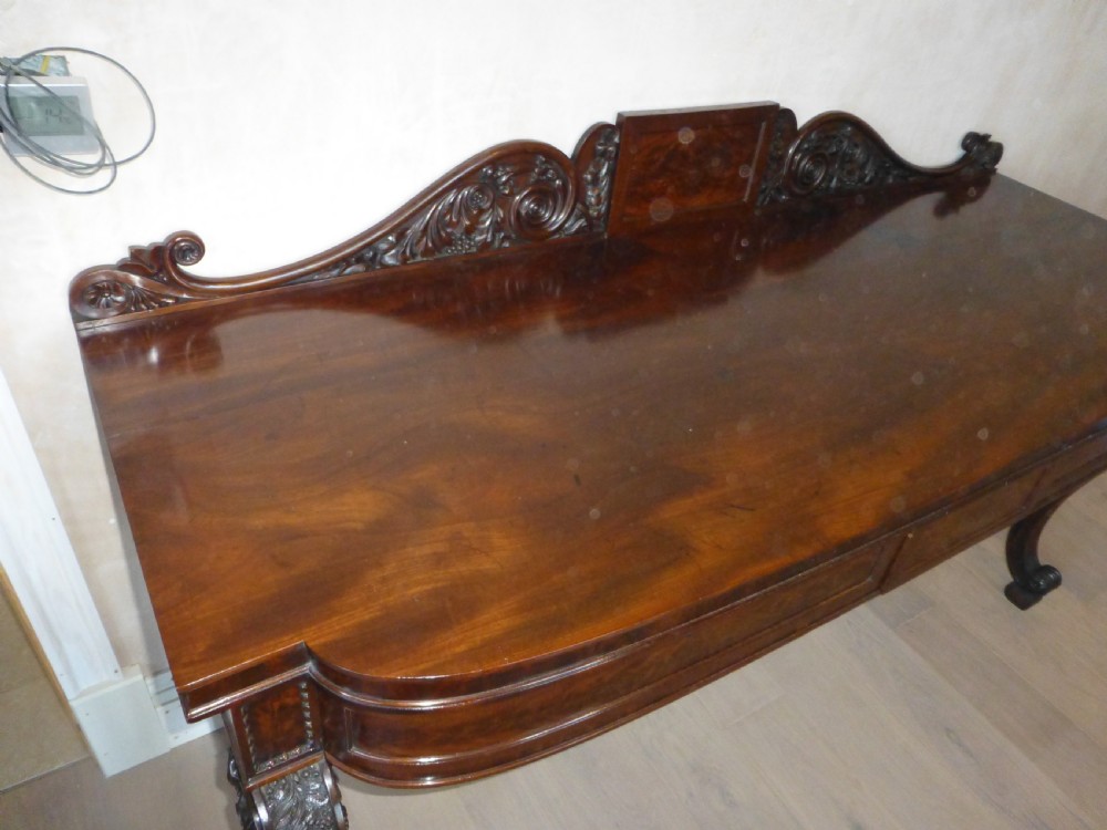 A dark mahogany Regency serving table featuring a scroll-carved backboard, a smooth top surface, and carved scroll front legs. View X