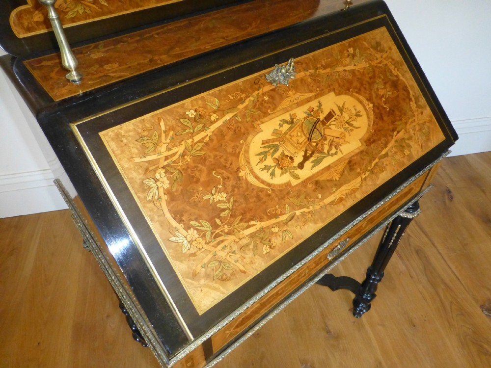 A nineteenth-century French slope-front writing desk featuring floral amboyna marquetry, ebonised turned legs with a shaped stretcher, and a brass gallery rail top. View II