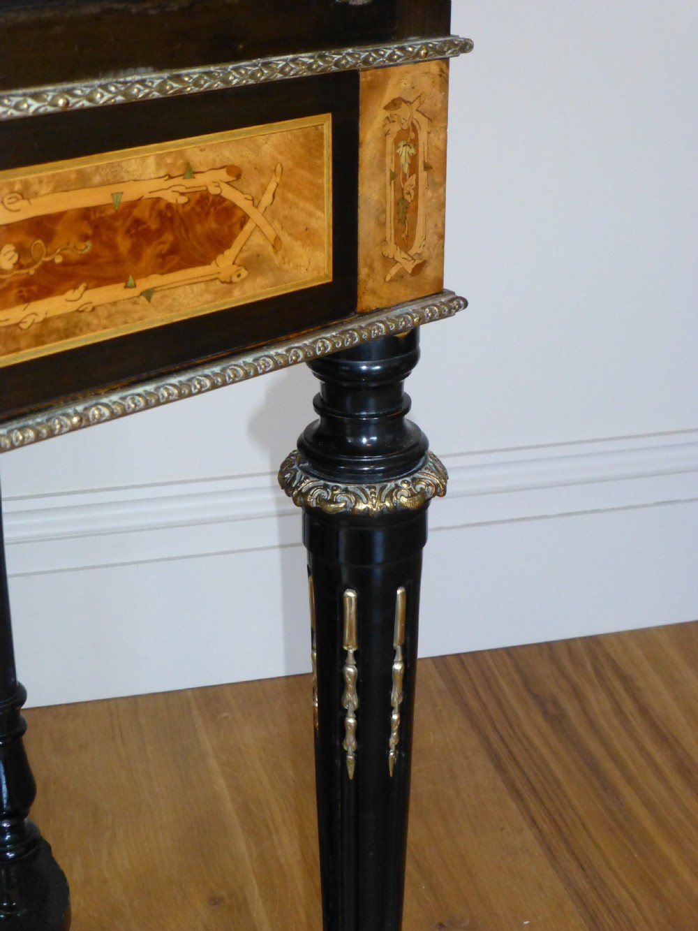 A nineteenth-century French slope-front writing desk featuring floral amboyna marquetry, ebonised turned legs with a shaped stretcher, and a brass gallery rail top. View III