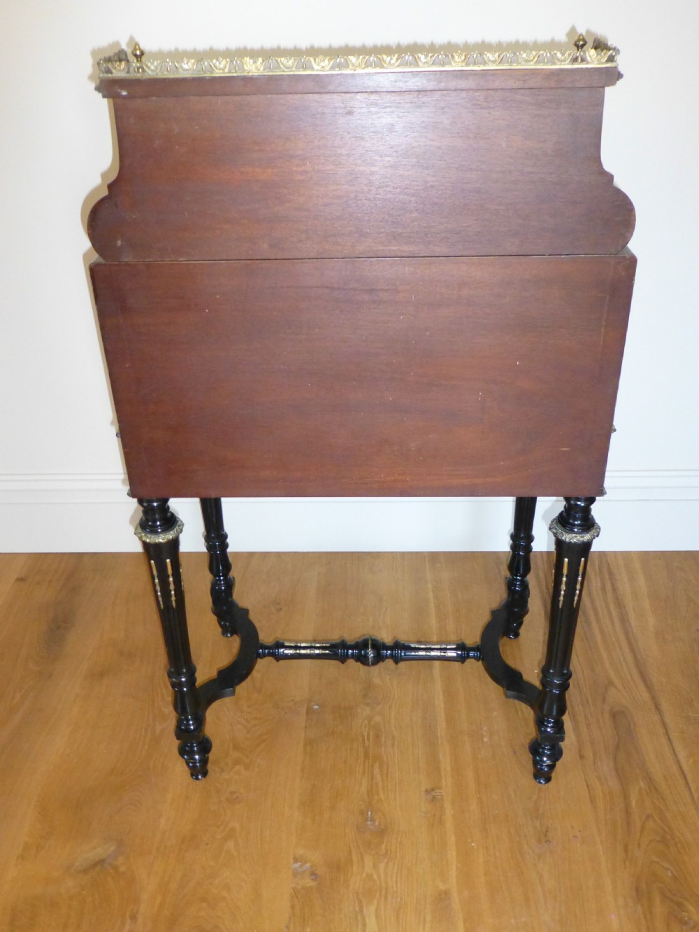 A nineteenth-century French slope-front writing desk featuring floral amboyna marquetry, ebonised turned legs with a shaped stretcher, and a brass gallery rail top. View XII