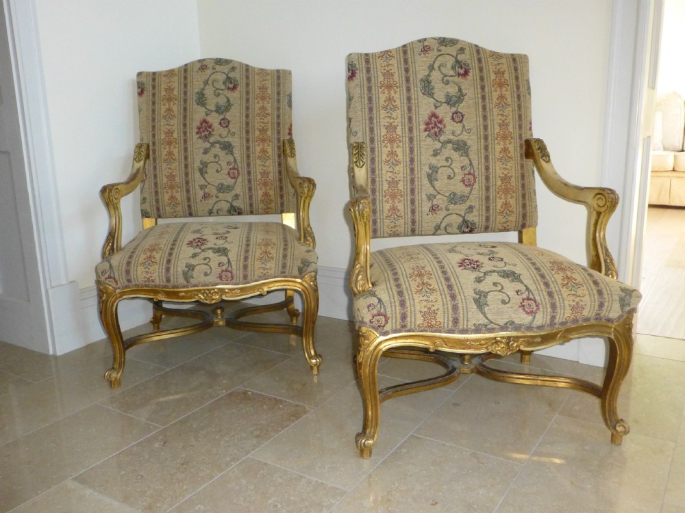 A pair of 19th-century giltwood Gainsborough salon armchairs with floral pattern upholstery and cabriole legs.