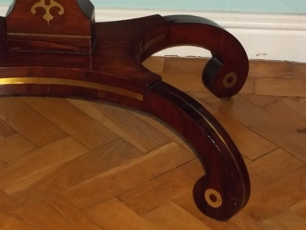 A Regency rosewood sofa table featuring drop leaves, brass inlay stringing, a central square pedestal, and splayed quadruped legs on castors. View VII