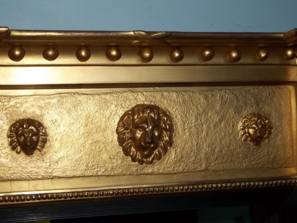 A tall Regency giltwood pier mirror featuring ball moulding along the cornice, a central frieze with lion masks, and fluted pilasters topped with Egyptian heads. View VI