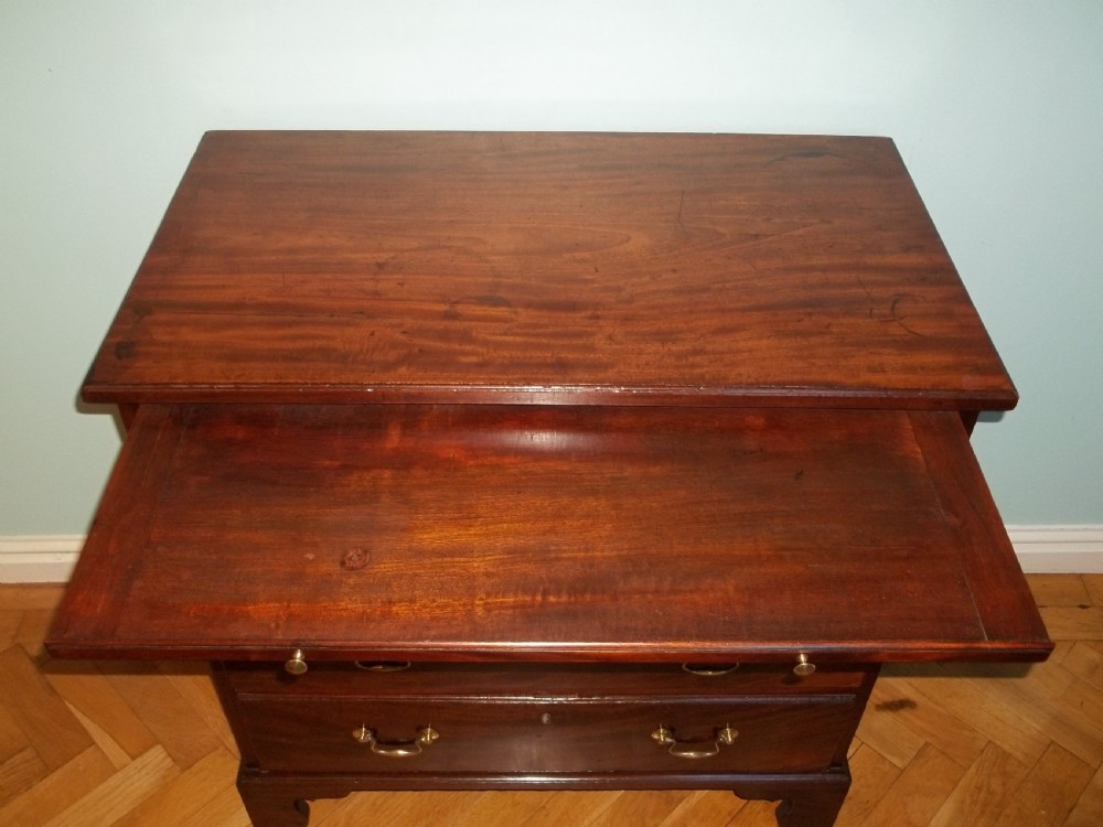 An eighteenth-century Georgian Cuban mahogany bachelors chest of drawers featuring an extended pull-out brushing slide and brass drop handles.