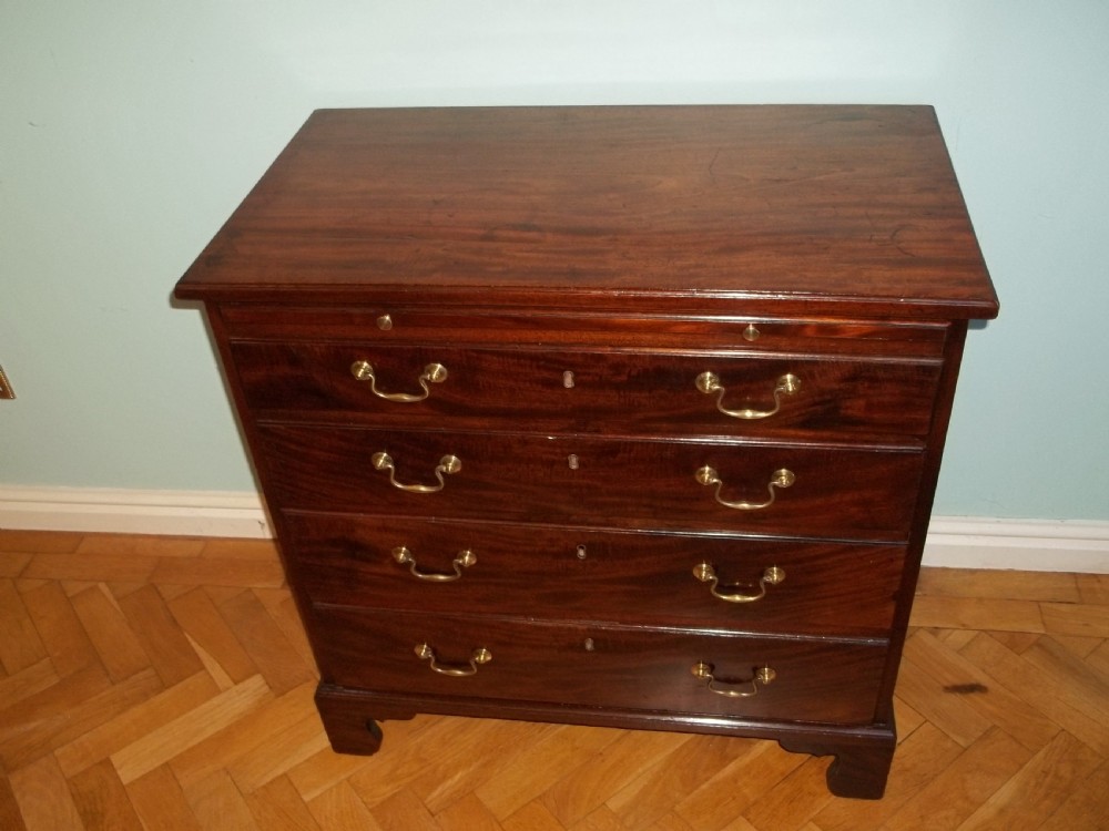 An eighteenth-century Georgian Cuban mahogany bachelors chest of drawers featuring an extended pull-out brushing slide and brass drop handles. View II