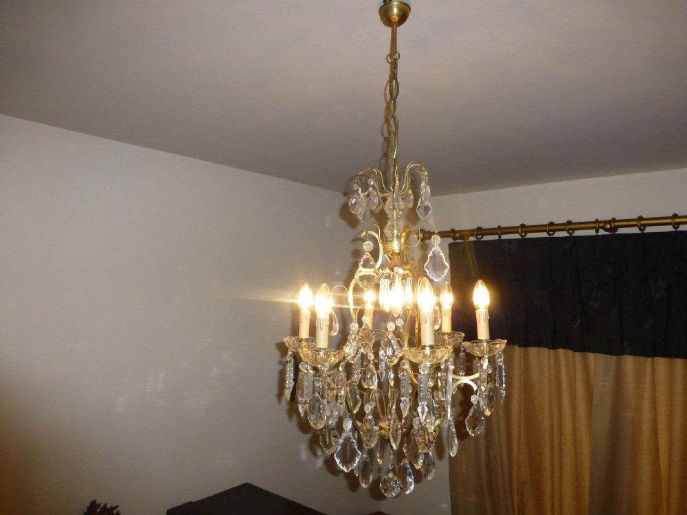 A late 19th-century French brass birdcage chandelier featuring multi-tiered cut crystal drops, glass candle sleeves, and central scrolling arms.