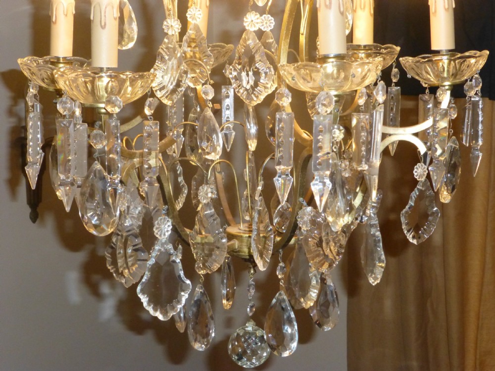 A late 19th-century French brass birdcage chandelier featuring multi-tiered cut crystal drops, glass candle sleeves, and central scrolling arms. View II