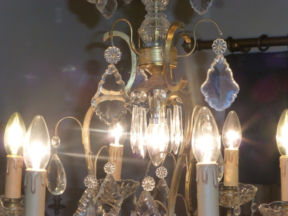 A late 19th-century French brass birdcage chandelier featuring multi-tiered cut crystal drops, glass candle sleeves, and central scrolling arms. View III