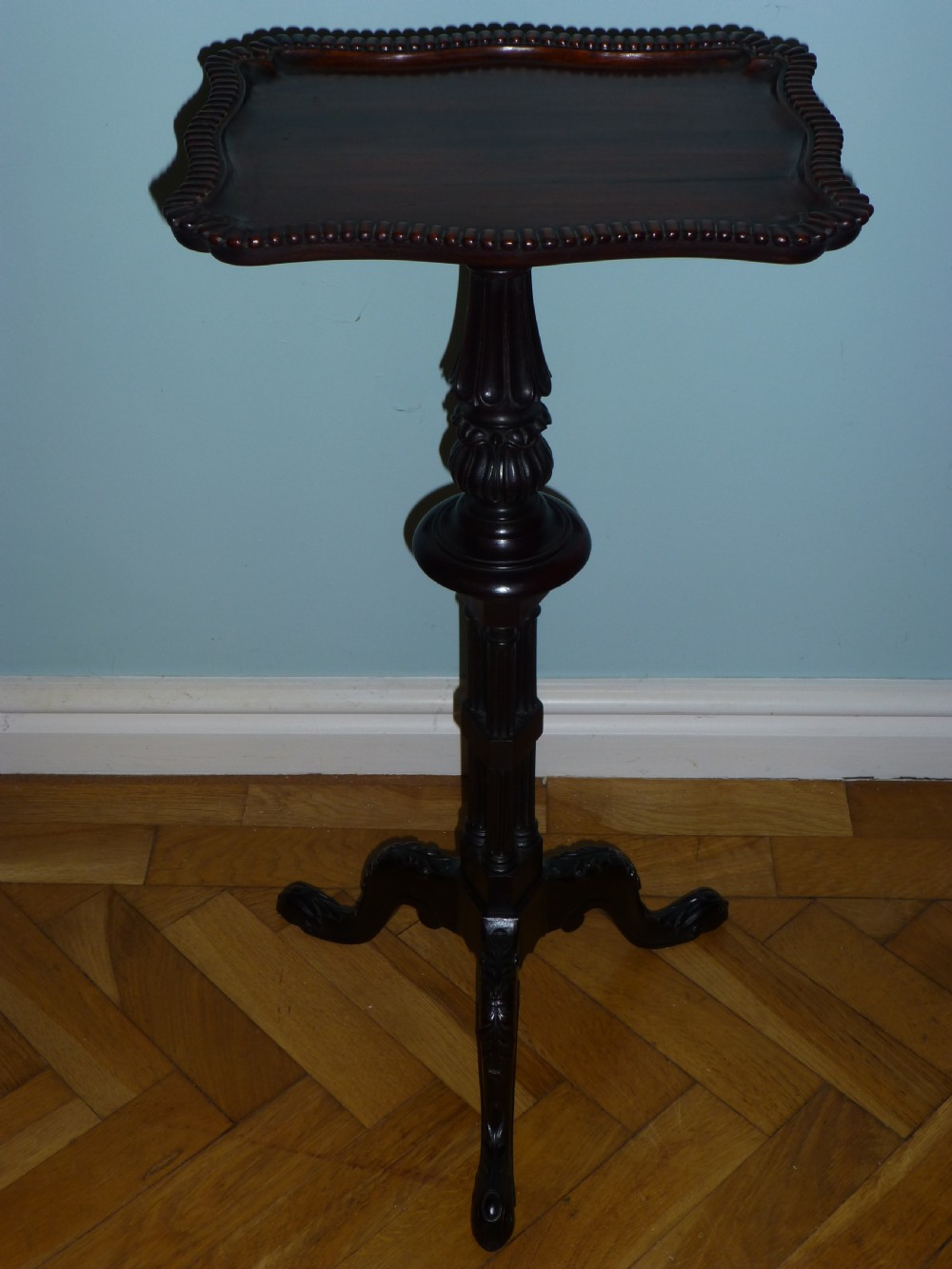 A dark brown Regency tripod side table featuring a carved rectangular pie crust top mounted on a turned pedestal shaft with three scrolled legs.