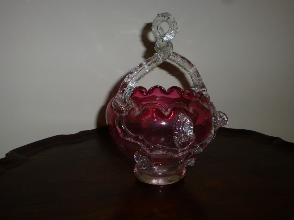 A nineteenth-century Victorian hand-blown cranberry glass bonbon dish with a crimped rim, clear glass overhead handle, and applied glass leaf accents. View II