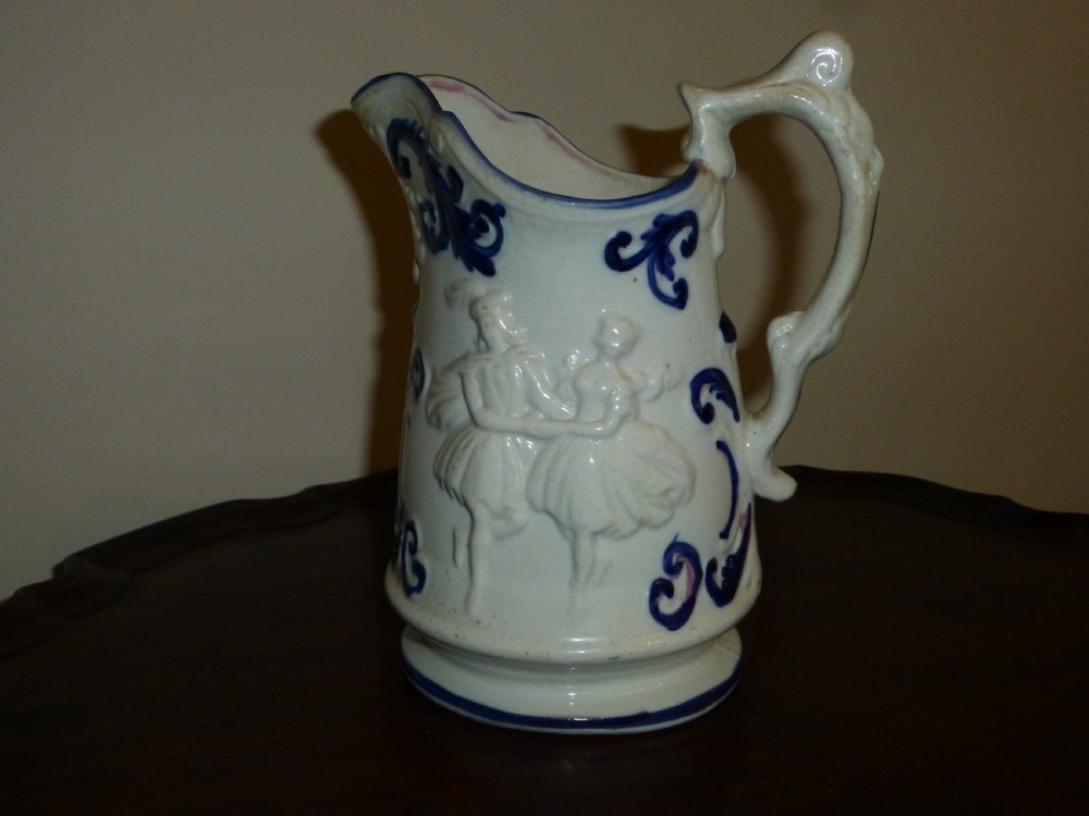 A white ceramic Staffordshire milk jug featuring raised relief mouldings and hand-painted cobalt blue scroll accents. View II