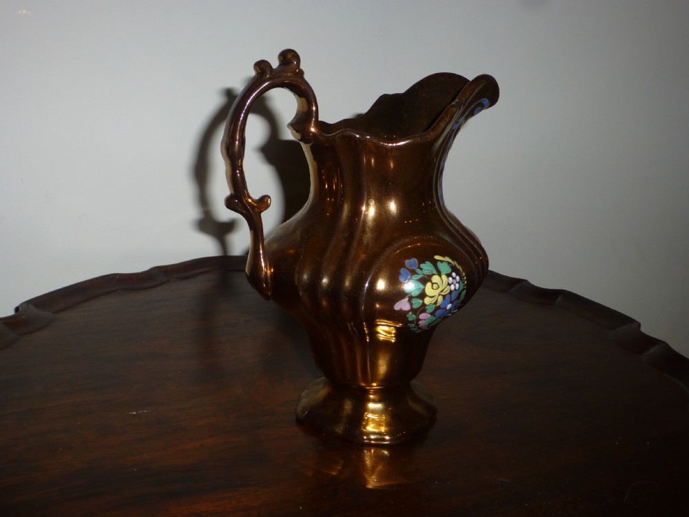 An antique copper lustre ceramic milk jug featuring hand-painted floral enamel details on a fluted body with a sculpted handle. View II