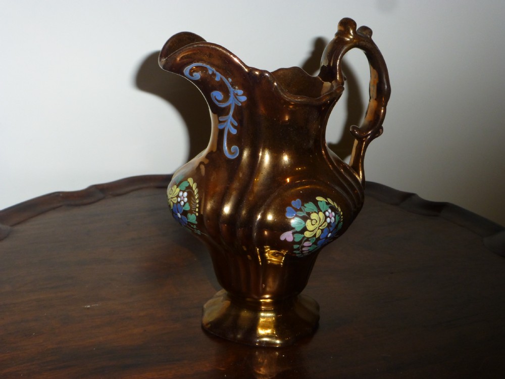 An antique copper lustre ceramic milk jug featuring hand-painted floral enamel details on a fluted body with a sculpted handle. View III