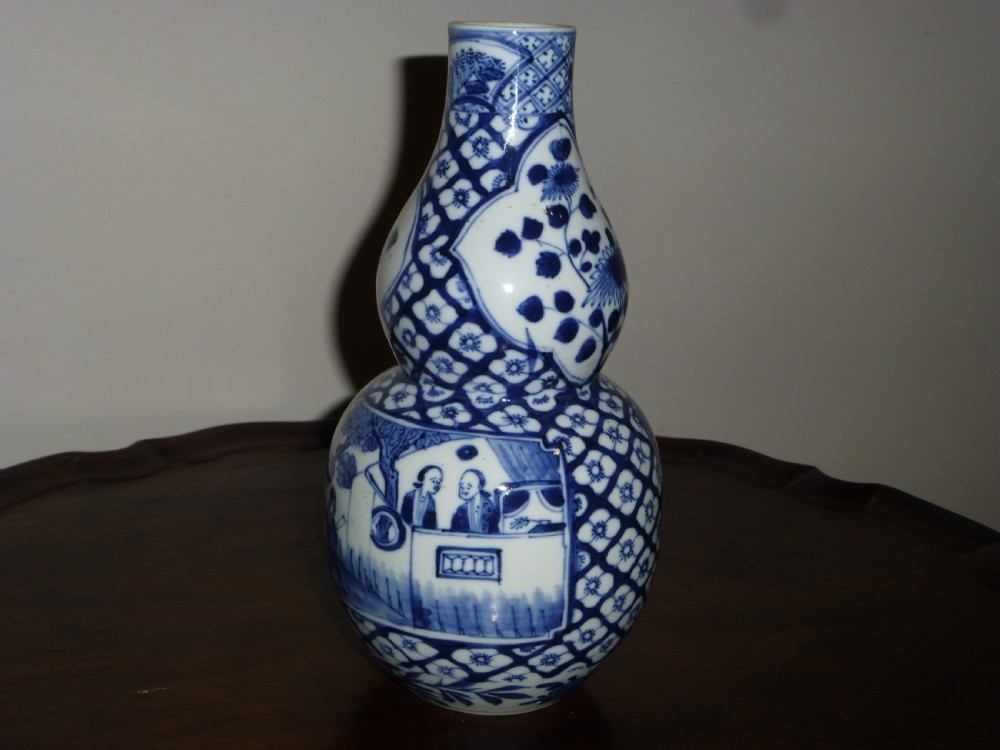 A Chinese blue and white porcelain double gourd vase decorated with figurative cartouches and floral diaper patterns.