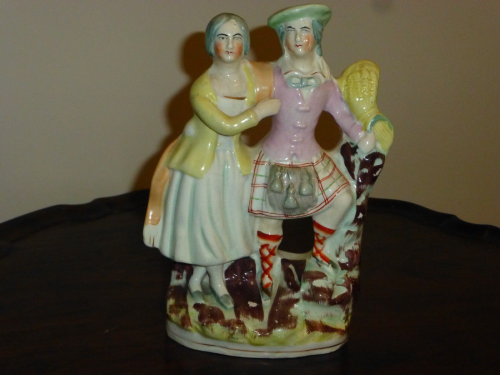 A Victorian Staffordshire flatback earthenware figure displaying a Scottish Laird in a tartan kilt alongside his wife in traditional dress.