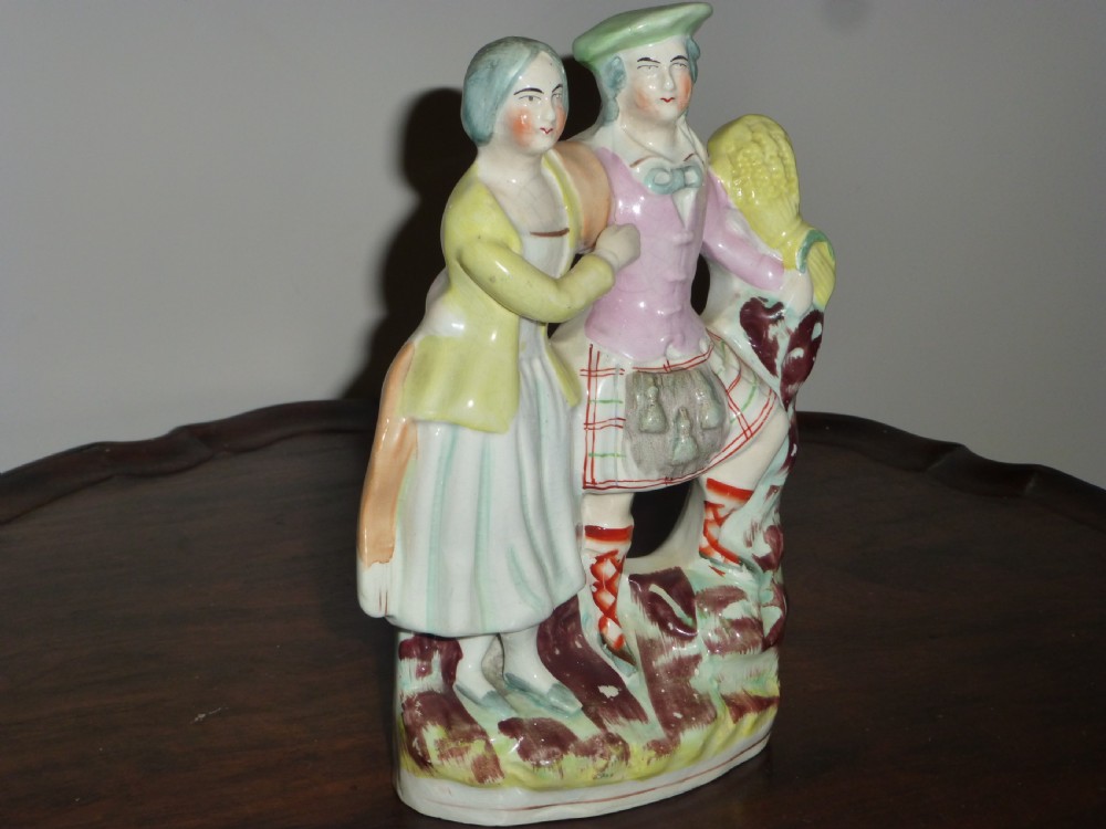 A Victorian Staffordshire flatback earthenware figure displaying a Scottish Laird in a tartan kilt alongside his wife in traditional dress. View II