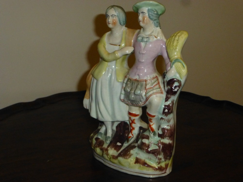 A Victorian Staffordshire flatback earthenware figure displaying a Scottish Laird in a tartan kilt alongside his wife in traditional dress. View III