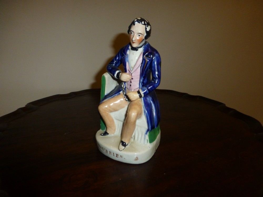 A Victorian Staffordshire earthenware portrait figure depicting Irish patriot William Smith OBrien seated in manacles, wearing a blue jacket and inscribed S. OBRIEN at the base. View III