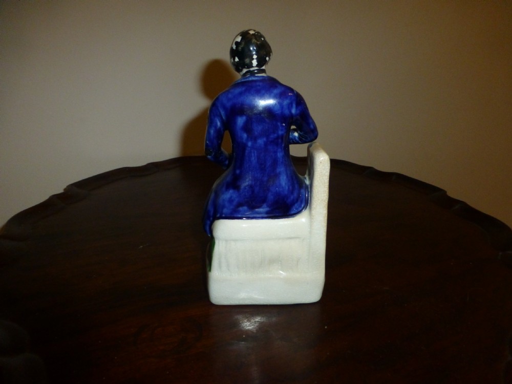 A Victorian Staffordshire earthenware portrait figure depicting Irish patriot William Smith OBrien seated in manacles, wearing a blue jacket and inscribed S. OBRIEN at the base. View VI