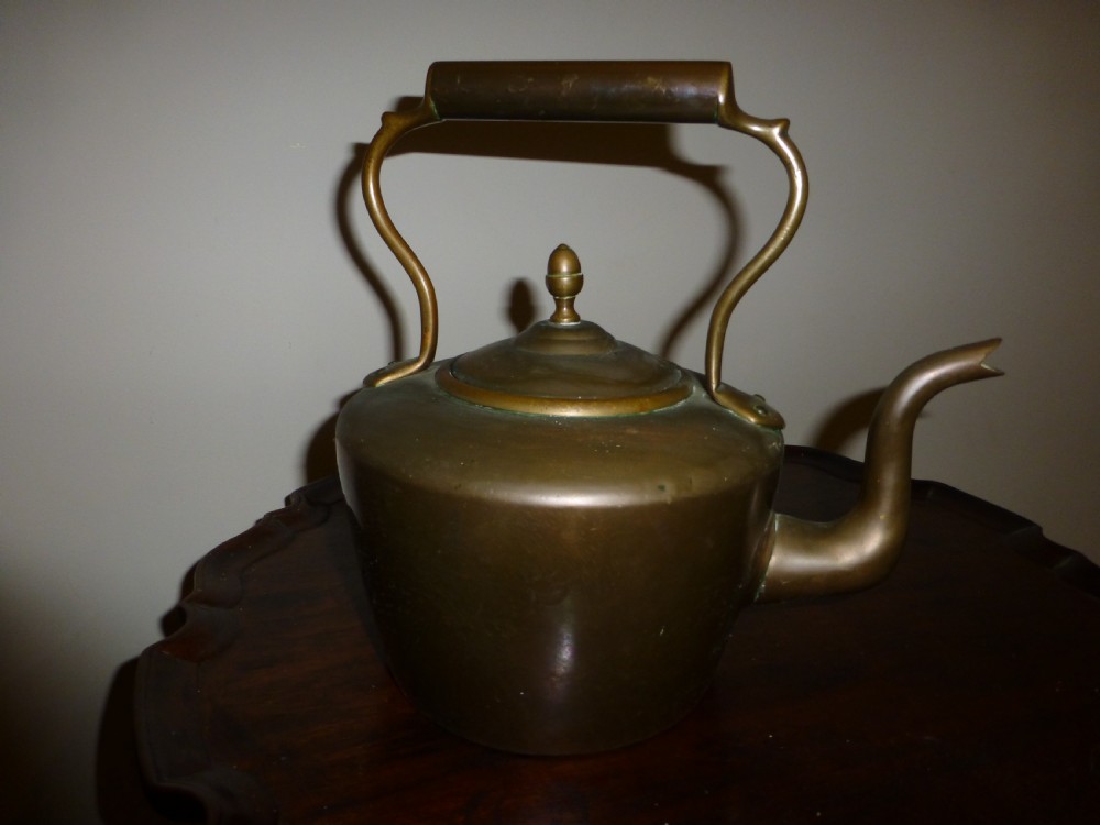 A George III Georgian copper tea kettle featuring an acorn finial, a curved gooseneck spout, and a fixed overhead handle.