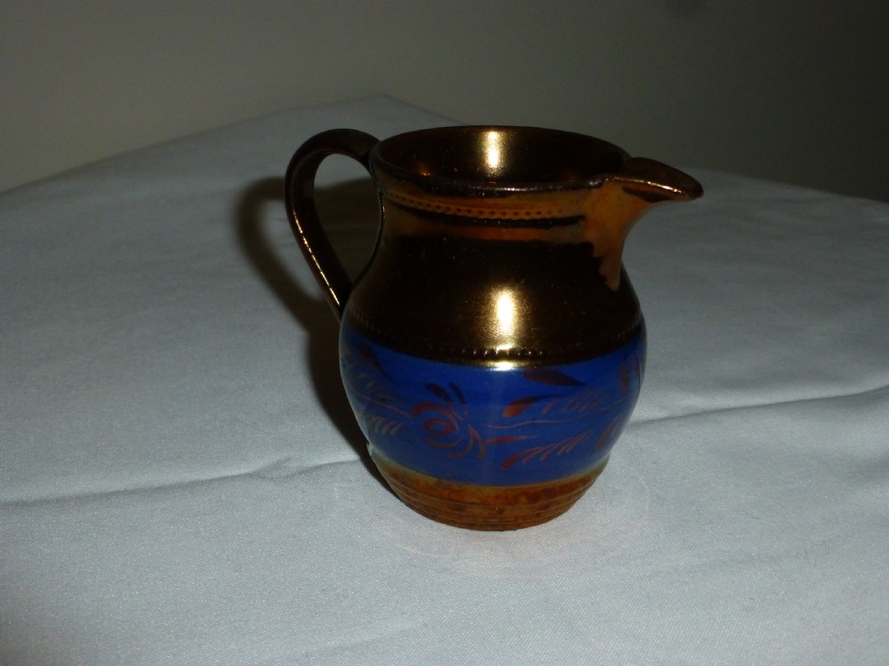 An antique Staffordshire ceramic cream jug with a metallic copper lustre body and a central bright blue band. View II