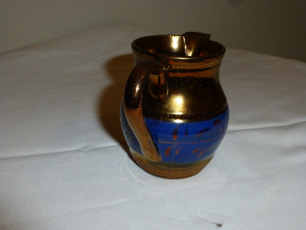 An antique Staffordshire ceramic cream jug with a metallic copper lustre body and a central bright blue band. View III