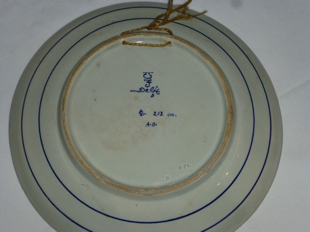 A circular 19th-century Delftware tin-glazed earthenware charger featuring a central hand-painted cobalt blue scene of sailing vessels on water surrounded by a floral rim pattern. View II