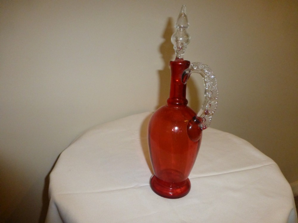 A Victorian cranberry red glass decanter featuring a clear glass moulded handle and clear glass stopper. View II