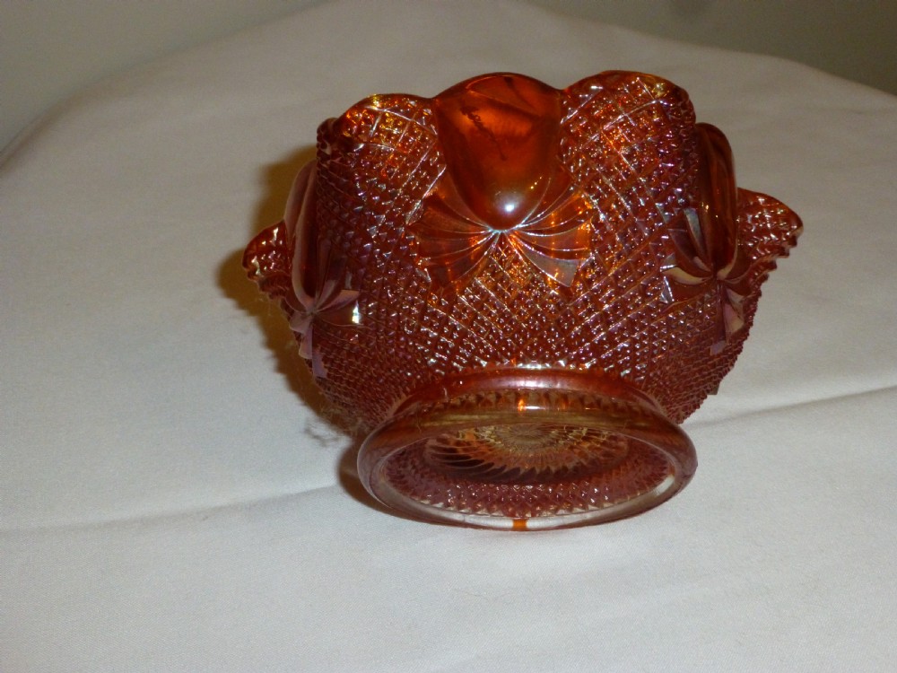 An amber iridescent carnival glass bowl with raised diamond press patterning and a scalloped rim.